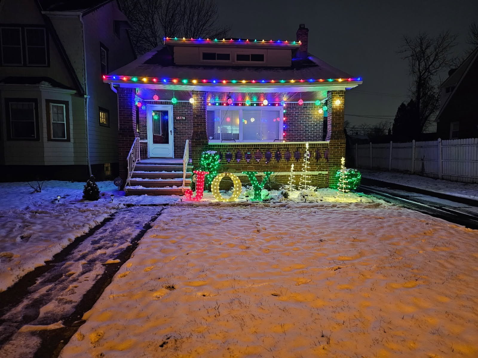 Colorful Christmas roofline and illuminated JOY lawn display